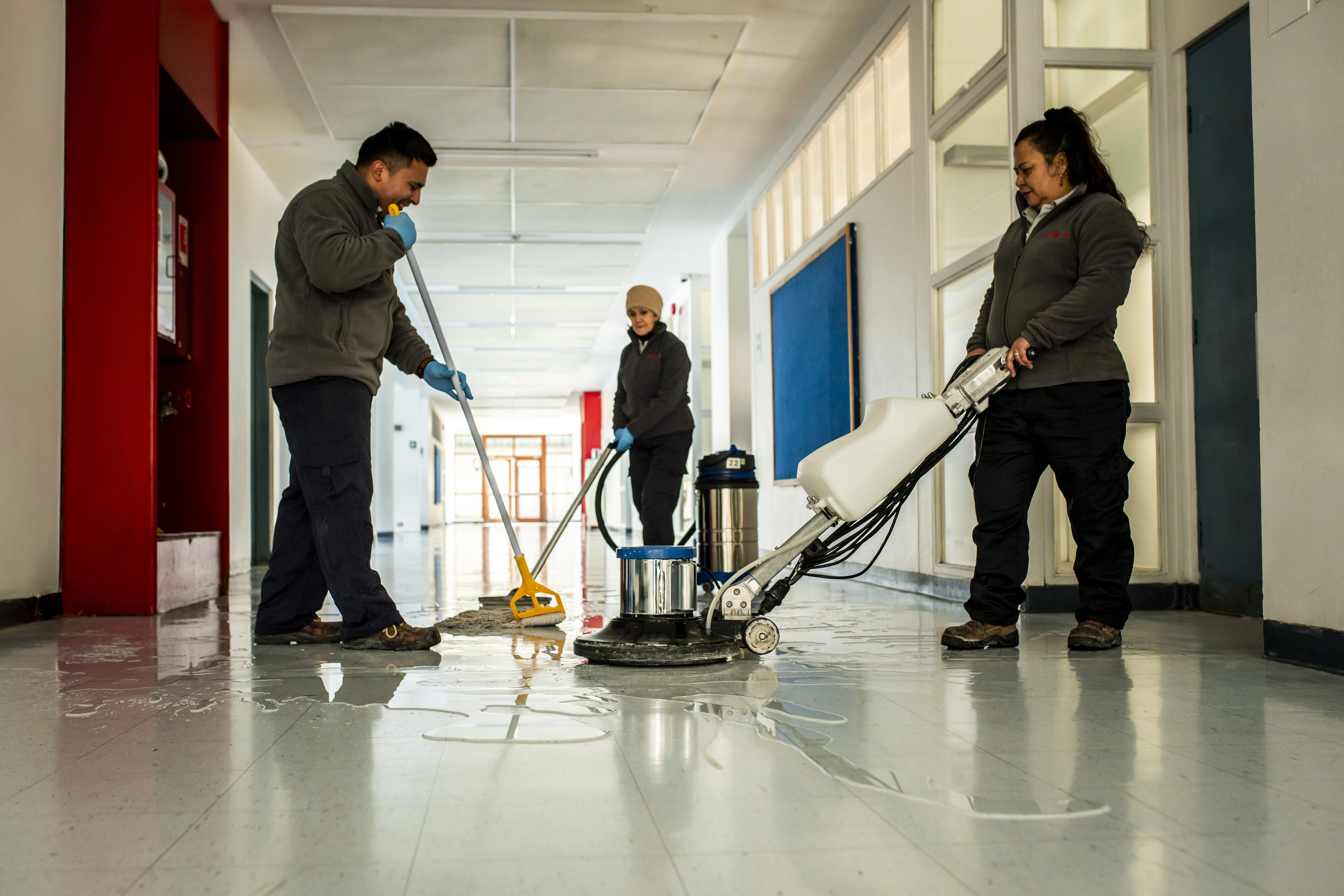 Equipo de tres profesionales de Guzmán y Schmidt trabajando en pasillo escolar